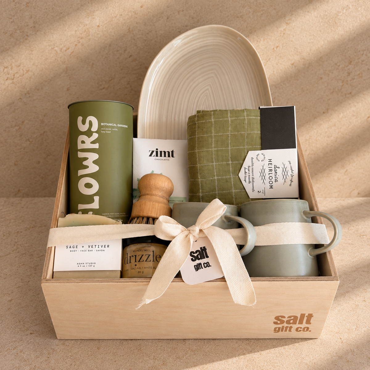 Handmade SALT Gift Co. maple crate with a ceramic serving dish, sage linen towel, Zimt chocolate, stoneware mugs, AGHA Studios soap and a wooden dish brush