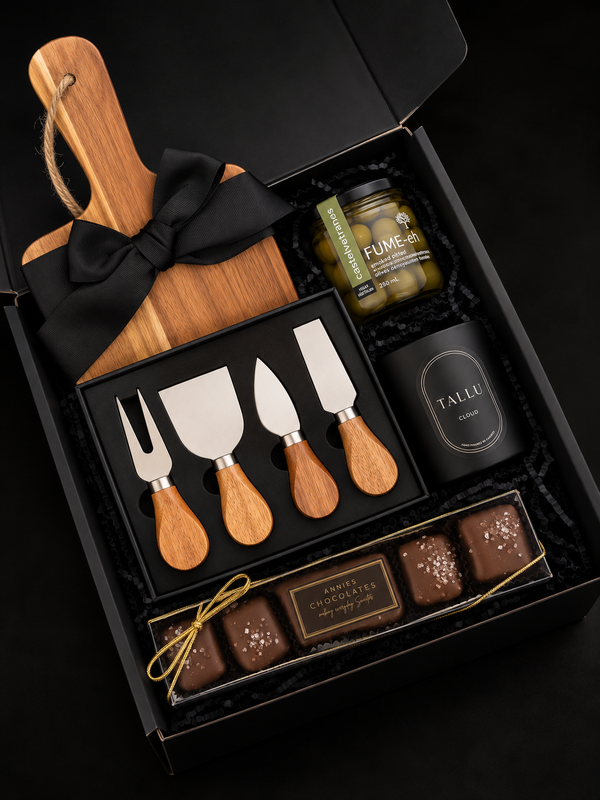 Luxury corporate gift box featuring an acacia serving board, wooden-handle cheese knife set, gourmet olives, and artisan chocolates, arranged in a black gift box with black ribbon.