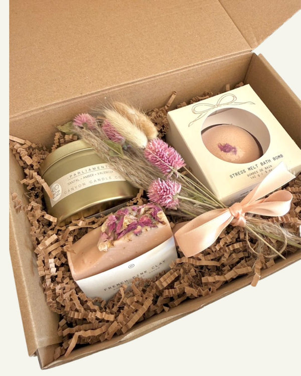 Small self care valentine's day gift box with a candle, bath bomb, and decorative florals in a box.