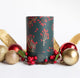 Holiday corporate gift box featuring Christmas tea, a ribbed ceramic mug, artisan chocolates, and a candle, styled with evergreen accents and brown ribbon in a black gift box.
