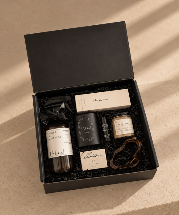 Westcoast Spa luxury gift box featuring TALLU Cloud candle, TALLU shower and sauna mist, Renaissance Poet Hand cream , Nordic Spa body scrub, Château Poet soap, So... perfume, and a tortoiseshell hair claw clip, arranged in black crinkle filler.